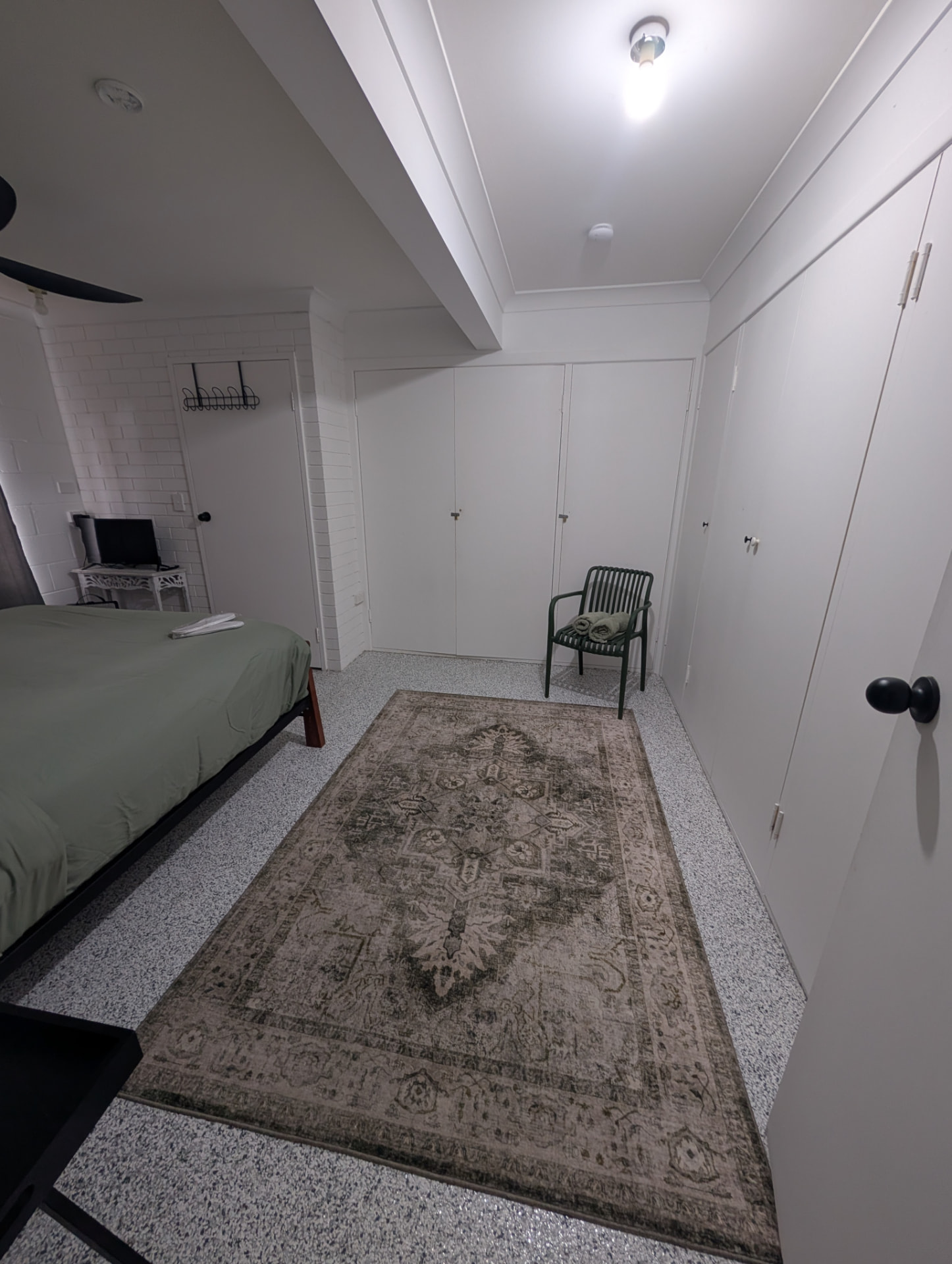 A second rental bedroom reset with fresh towels laid out on the chair